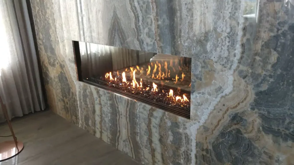 see thru linear gas fireplace with marble facade and frameless view