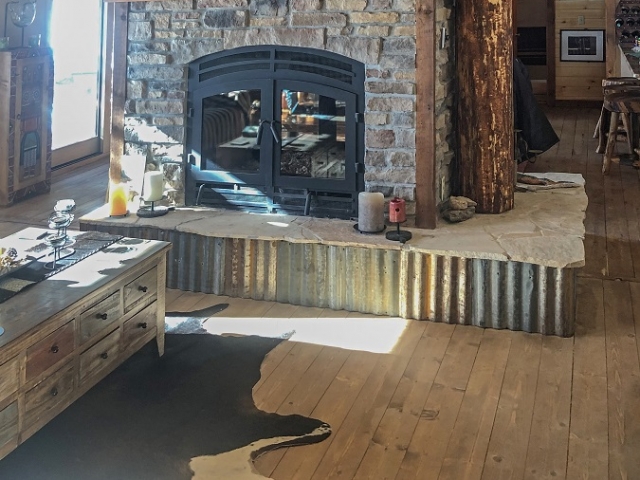 see through wood burning fireplace in cabin with exposed flue
