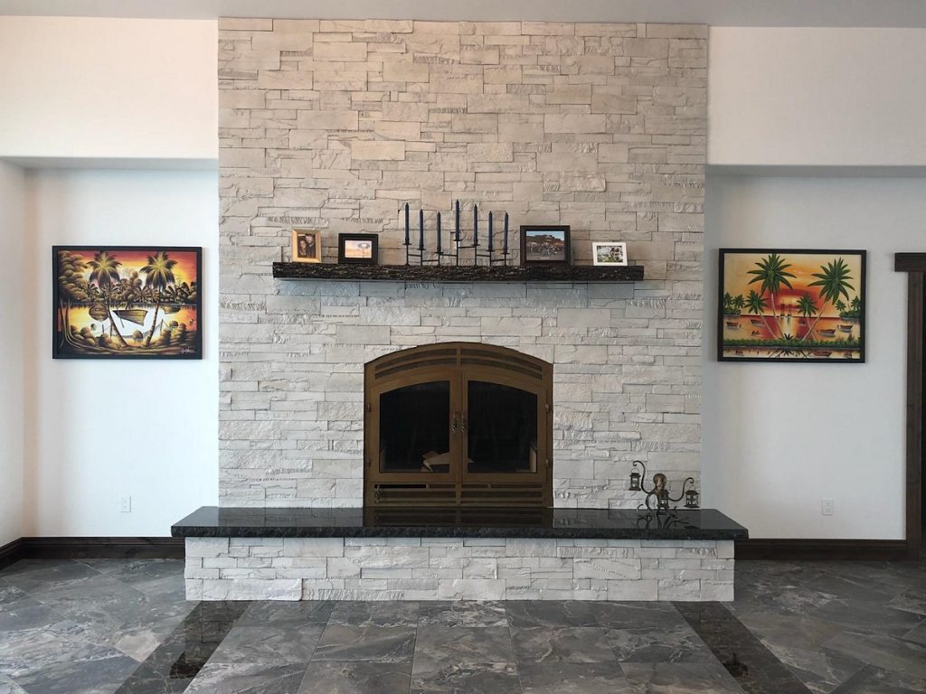 a wood-burning fireplace in a living room between two portraits