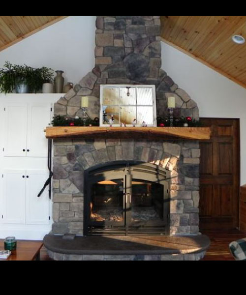 single sided wood burning fireplace with stone surround in living room