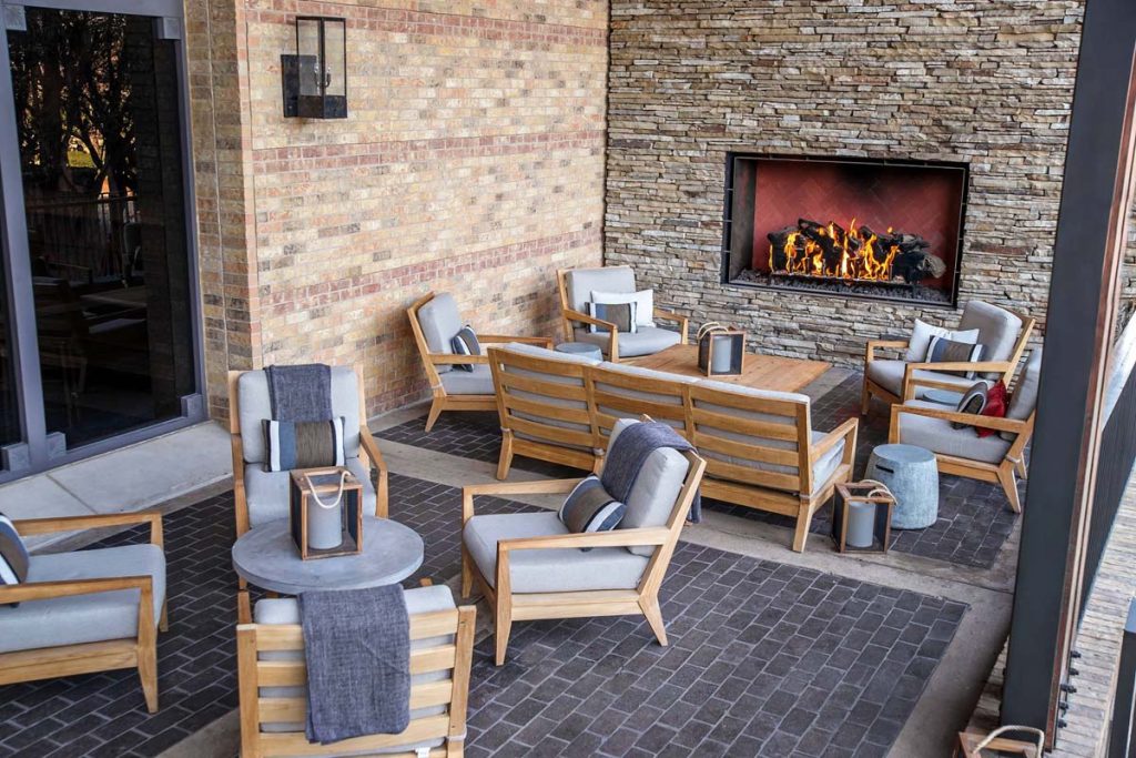 a photo of the four seasons dallas resort patio with a large open view fireplace with gas logs