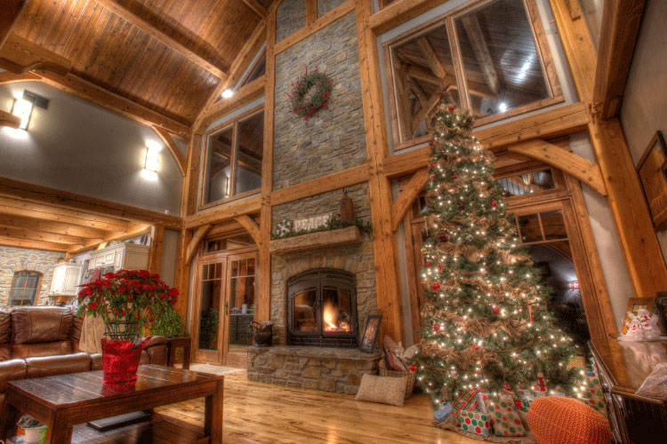 a double-sided fireplace in a cabin living room by a Christmas tree