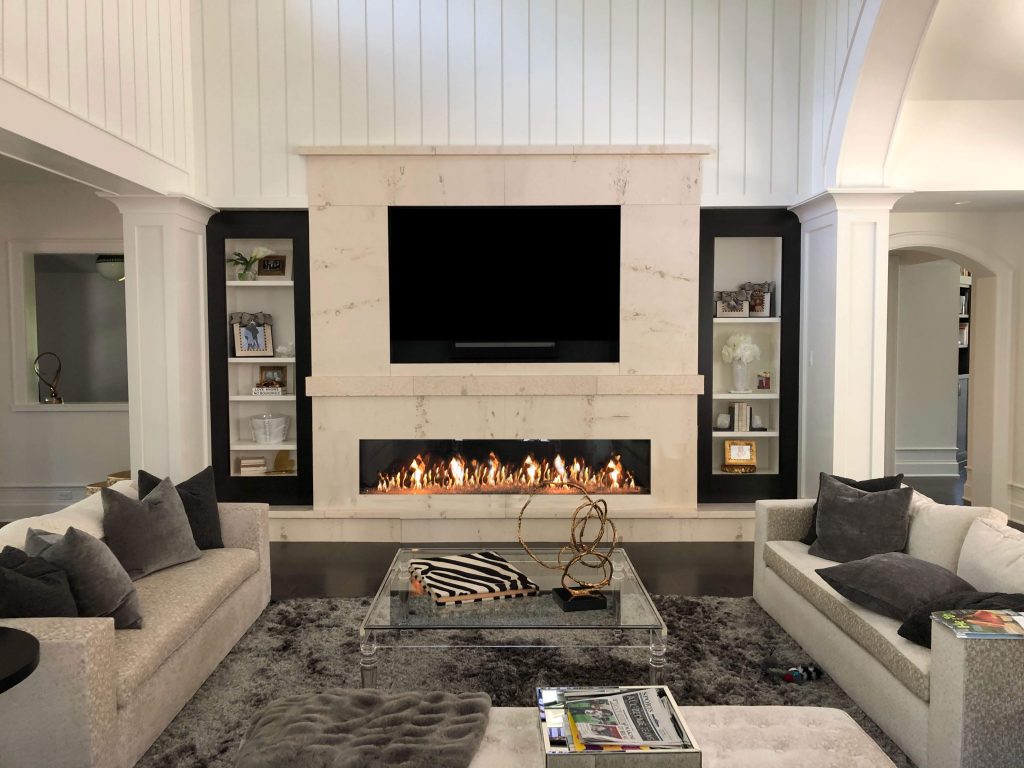 A living room with a white marble gas fireplace