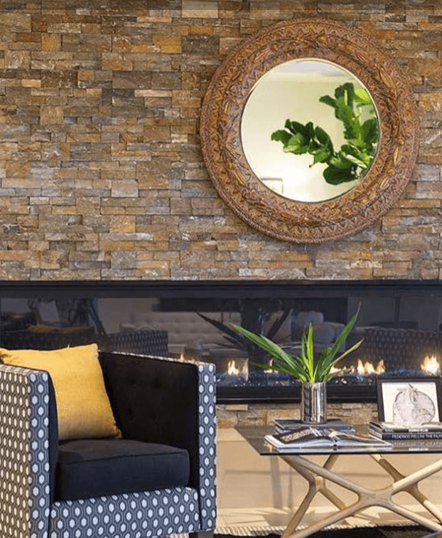 Chair covered in shapes and patterns in front of a stone wall and a linear fireplace