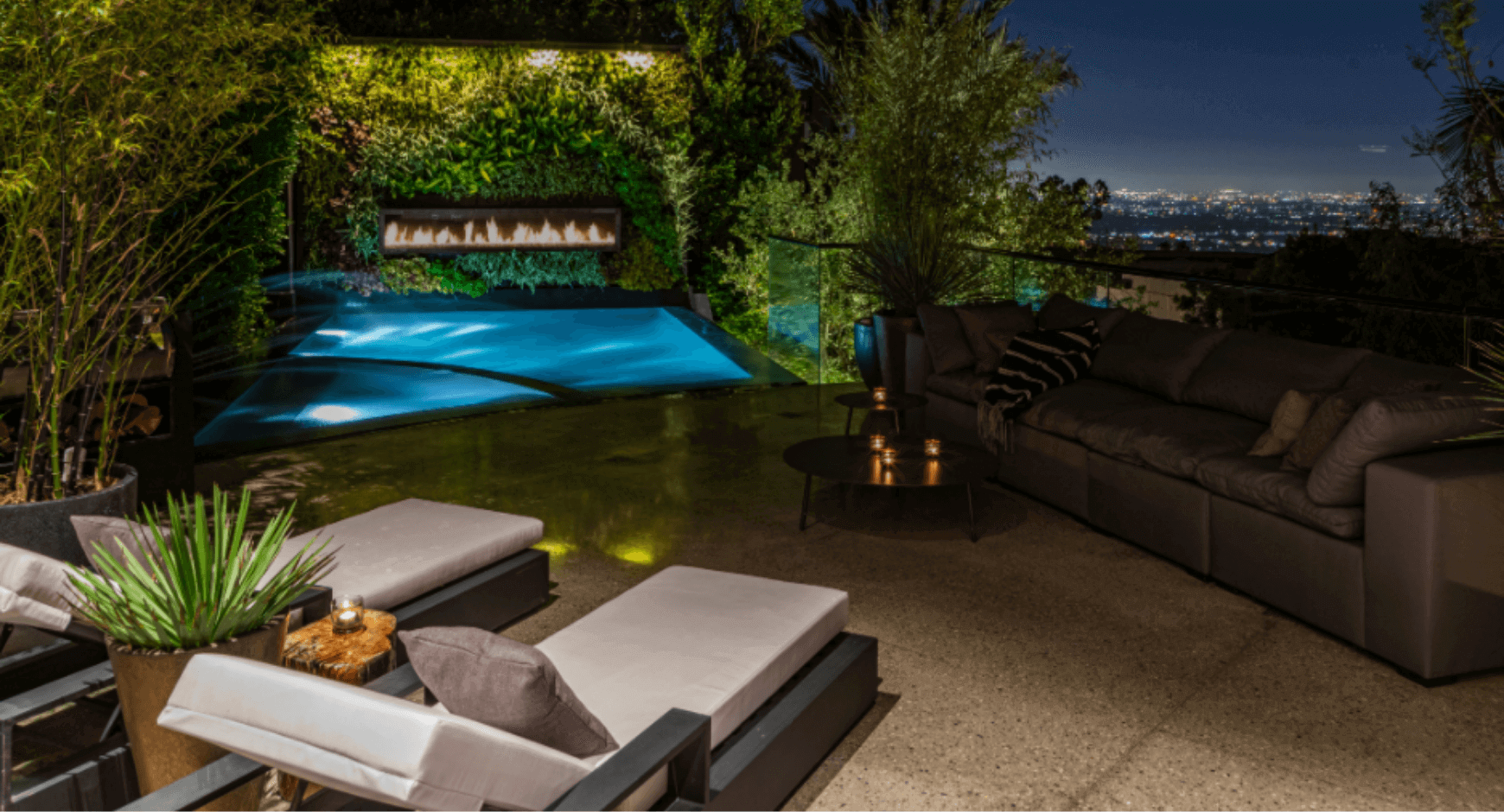 Linear poolside fireplace at night overlooking a city