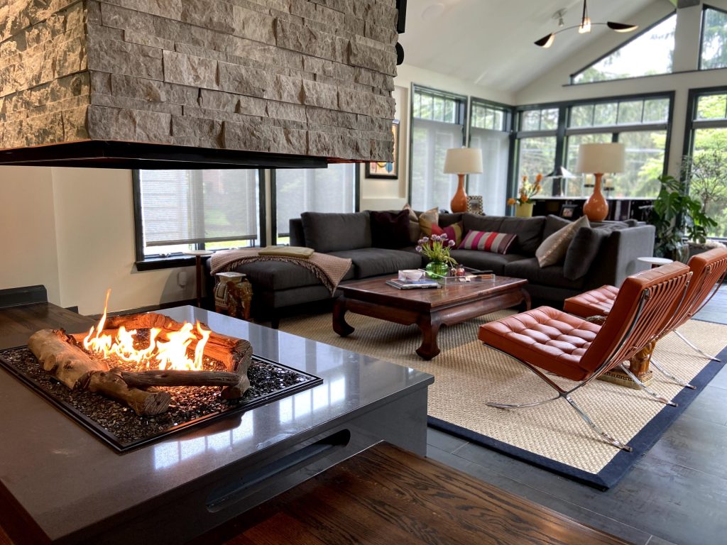 A living room with a four sided fireplace and colorful furniture