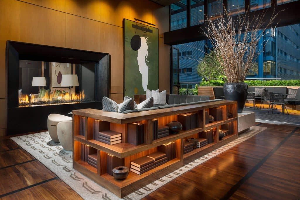 a lounge area in a hotel with art on the wall and a see through fireplace