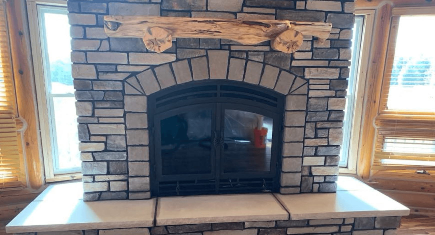 Clean stone fireplace with black doors and dark mortar