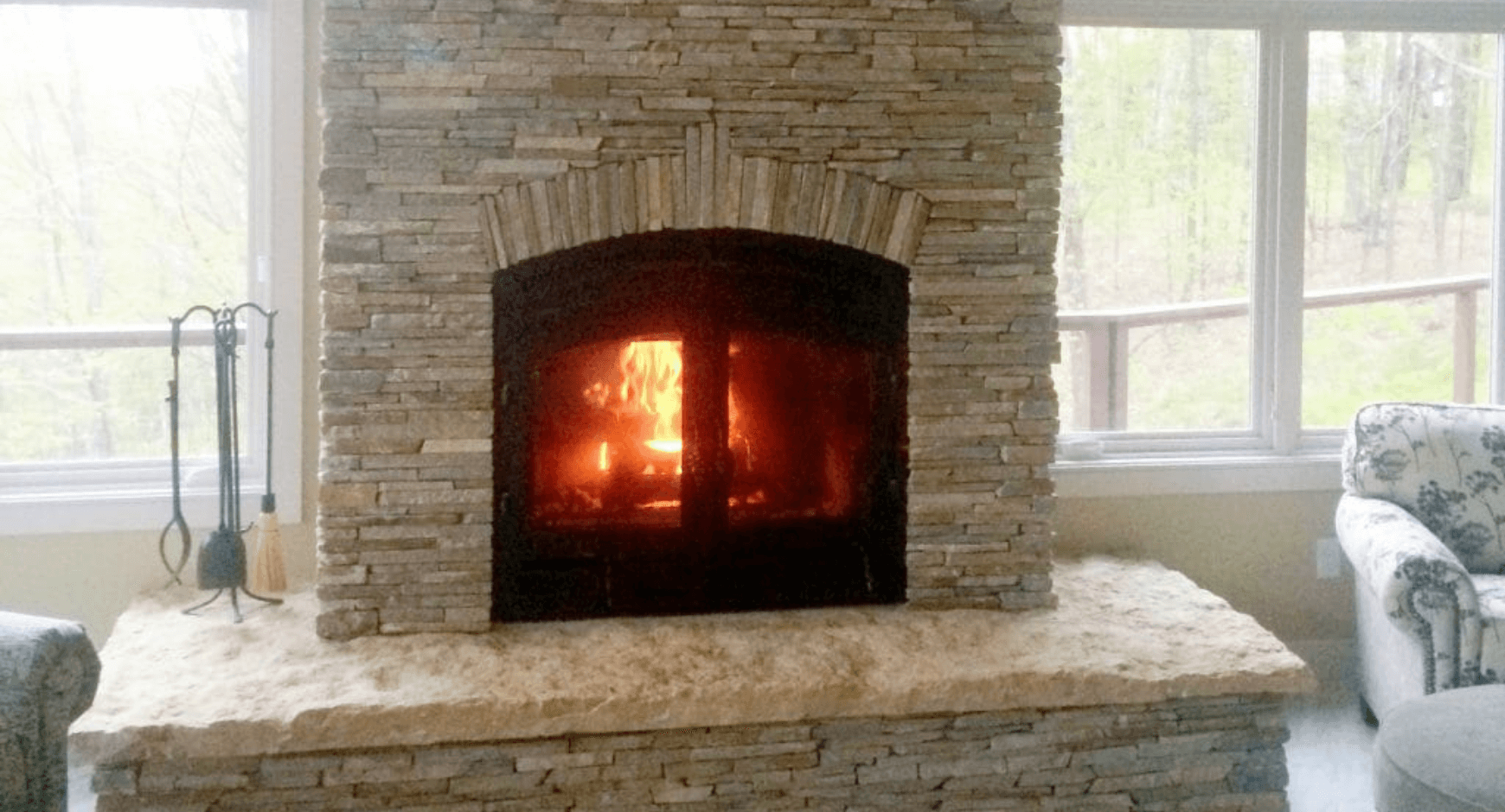 A lit fireplace surrounded by thin stacked stone