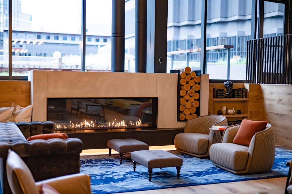 a gas fireplace in a hotel lobby with a stack of wood built into it