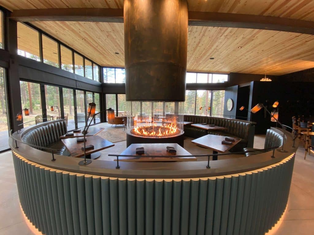 a large circular fireplace that is surrounded by a circular booth and tables