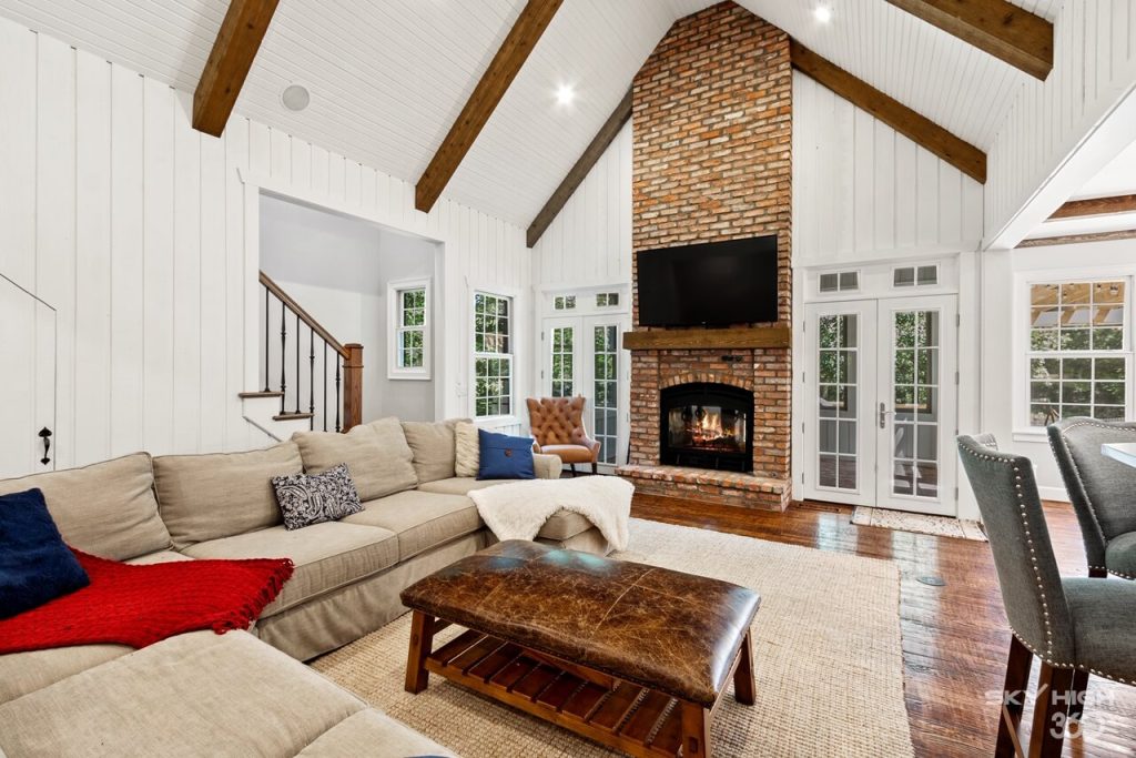 A living room with a wood burning fireplace brick design and leather ottoman