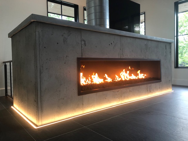 a photo of a concrete surrounded linear gas fireplace with an open viewing area