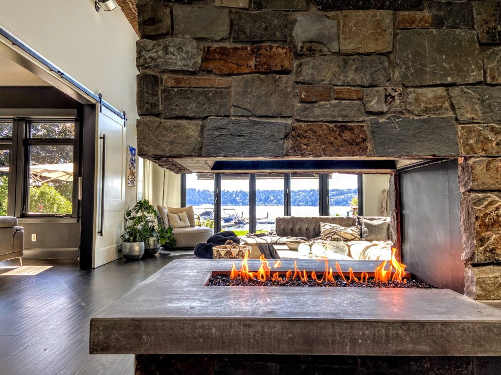 an open hearth stone 3 sided gas fireplace overlooking the lakeview living room
