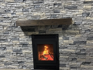 front facing wood fireplace with gray stacked faux stone finish
