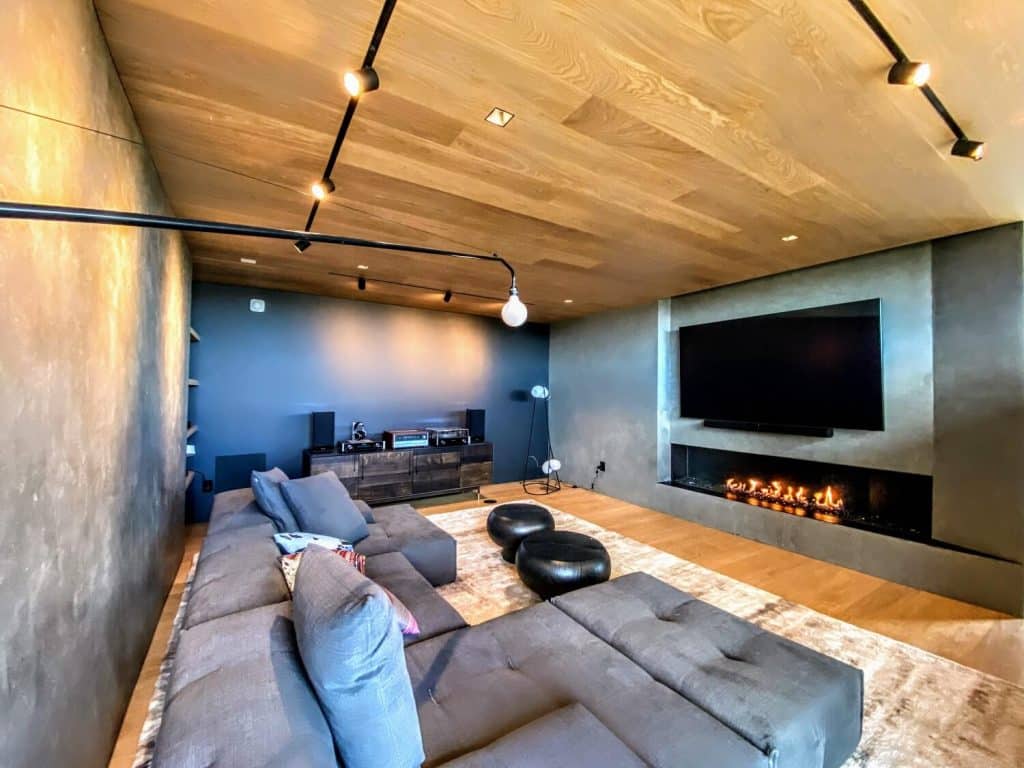 A living room with a linear fireplace and music system