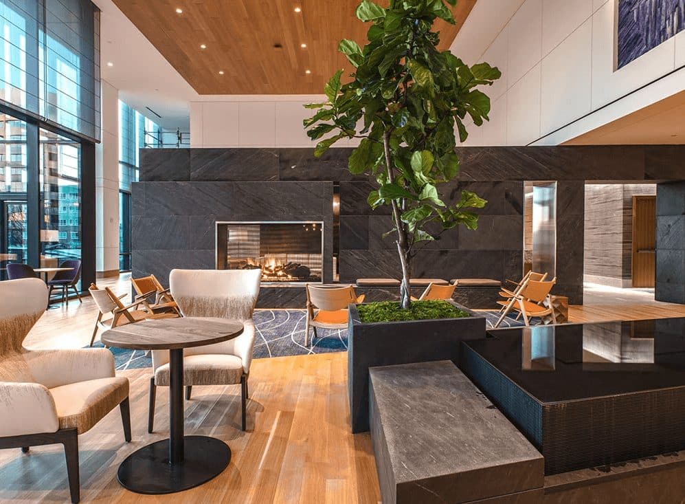 a hotel lobby with a large tree by a seating area and fireplace