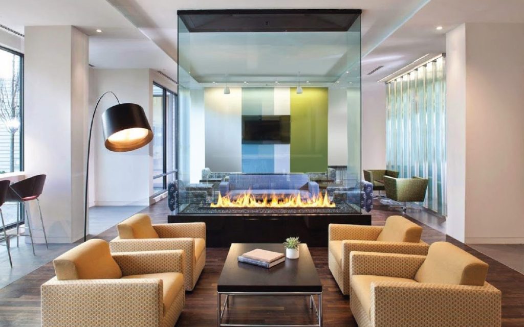 A sleek four-sided gas fireplace in an open-concept living space, offering a view of the flames from every angle.