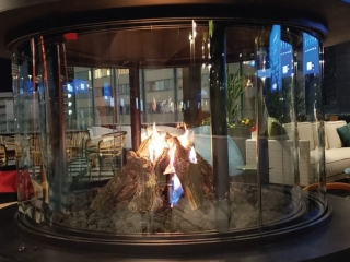 a custom outdoor gas fireplace with teepee gas logs on rooftop lounge