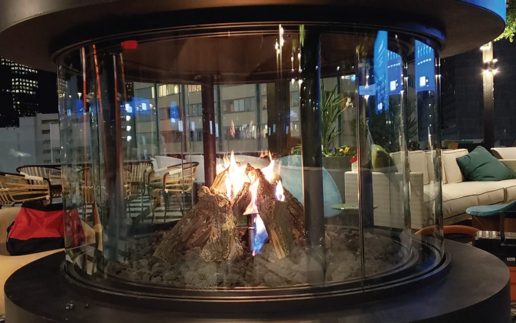 a custom outdoor gas fireplace with teepee gas logs on rooftop lounge