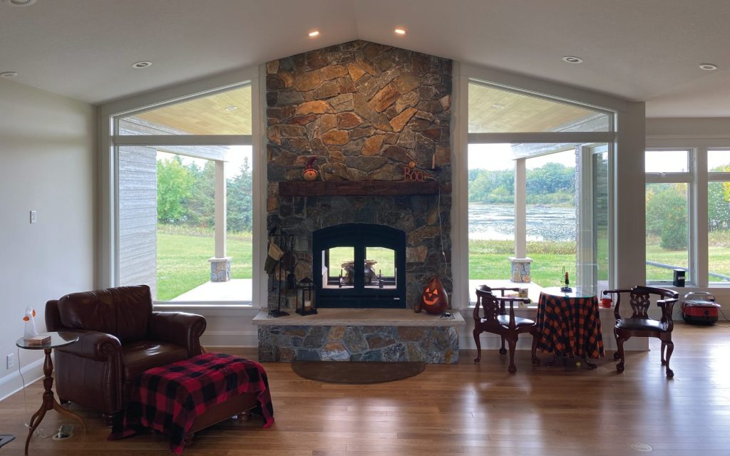 a double sided wood burning fireplace with blower in a cabin overlooking a lake