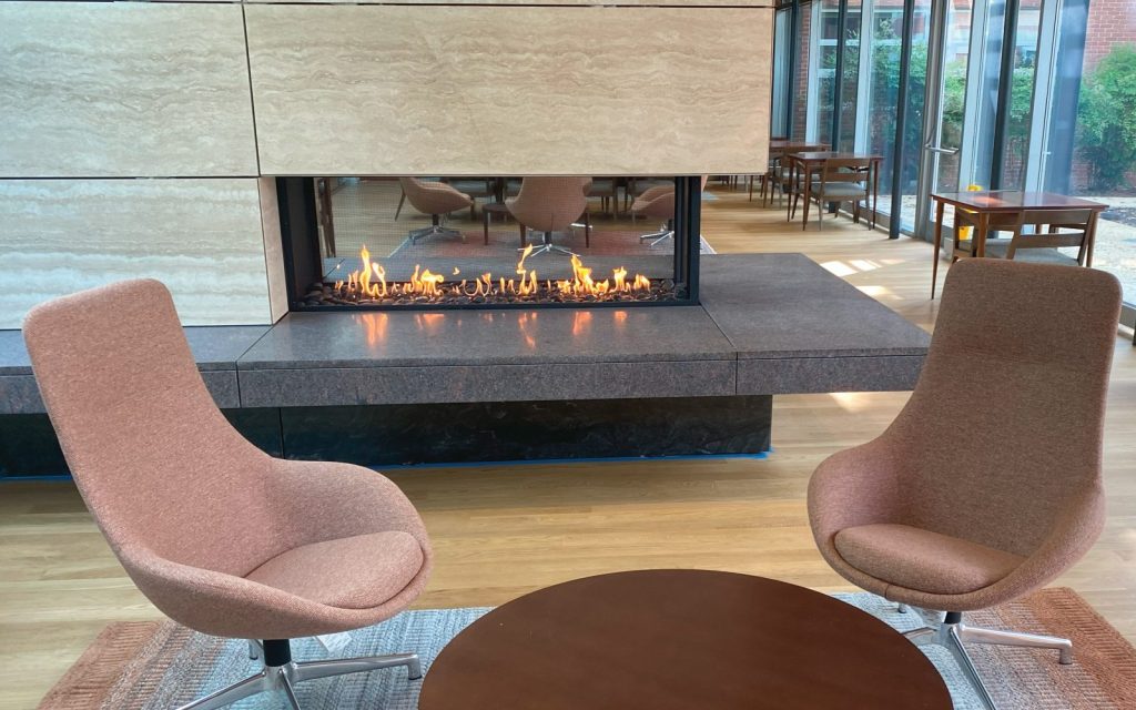 an open flame gas fireplace with firescreen in a student lounge