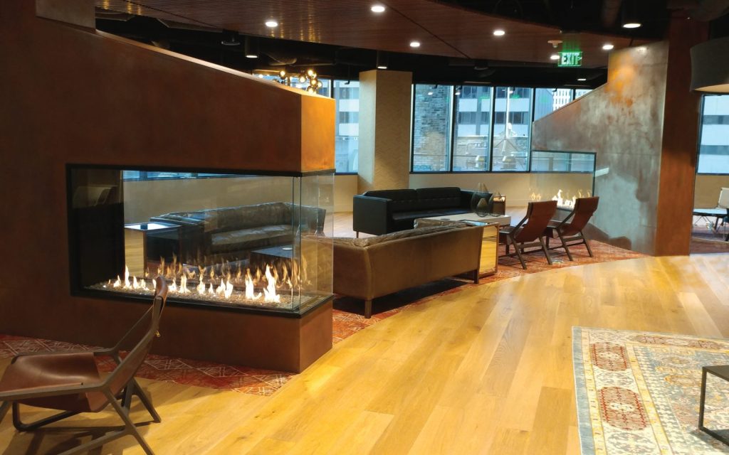 dual peninsula indoor gas fireplaces in office amenity lounge