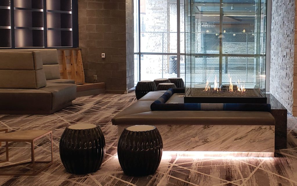 a glass fireplace with cushioned seating in lobby
