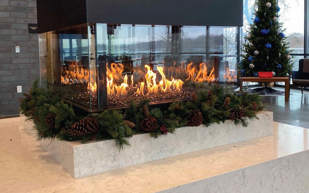 a multi sided gas fireplace with holiday decorations