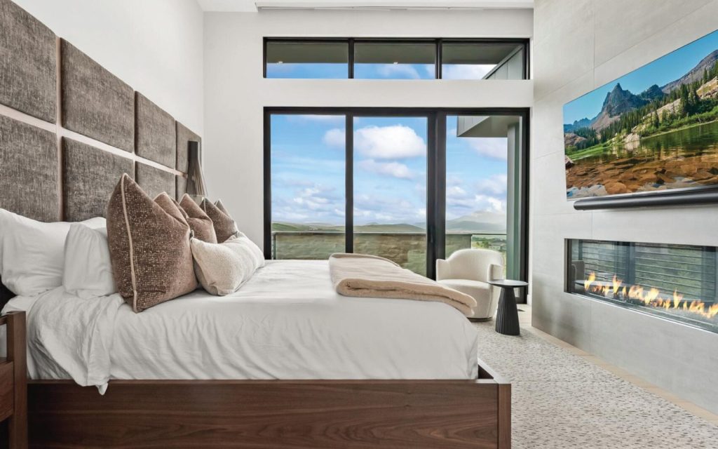 a linear gas fireplace in a bedroom overlooking the mountains