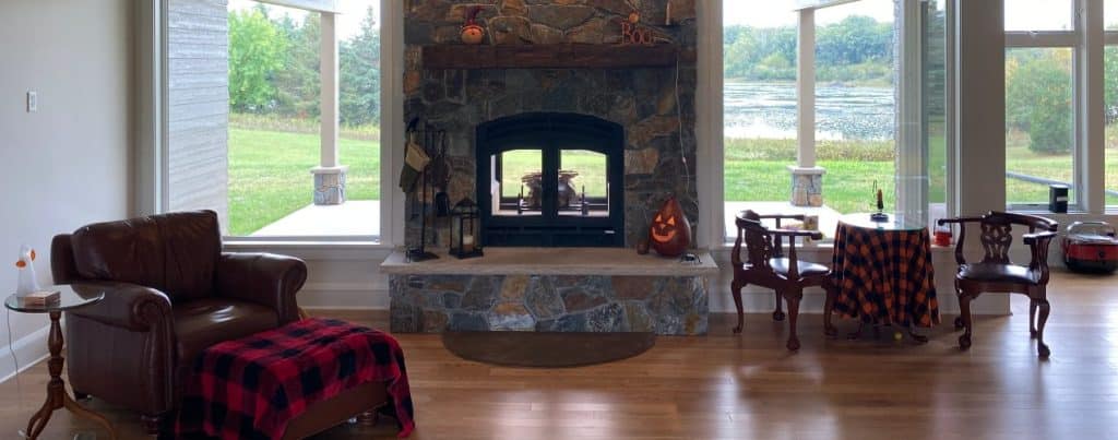 wood burning fireplace inside outside see thru with stone finish in living room overlooking a lake