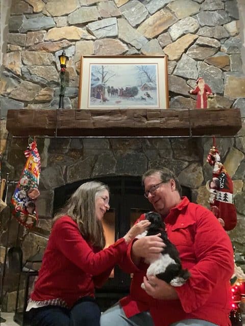husband and wife with their puppy in front of an acucraft wood fireplace