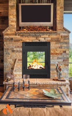 rustic double sided wood burning fireplace with stone finish and tv above