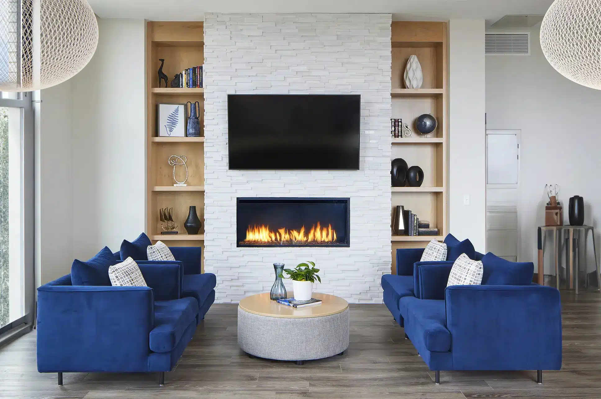 an image of a modern living room with a linear fireplace with tv and contemporary blue couches