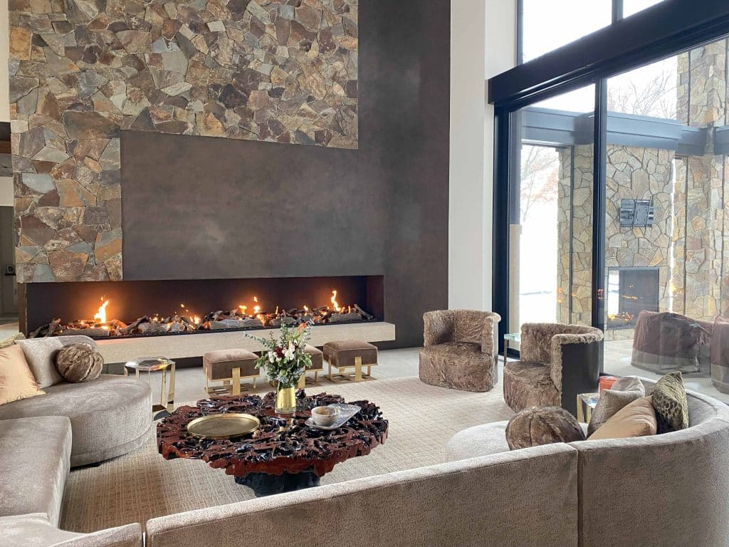 Elegant living room with a large, open front and side gas fireplace with driftwood logs