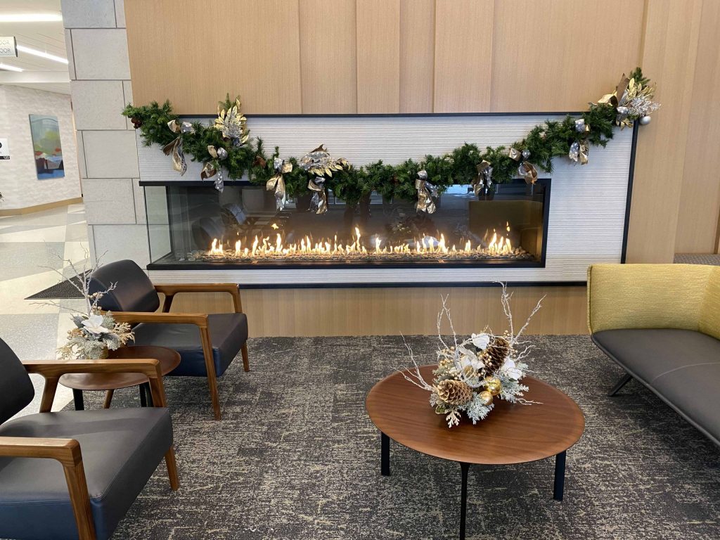A modern front and side view gas fireplace installed in a cozy corner, showcasing flames visible from two perspectives