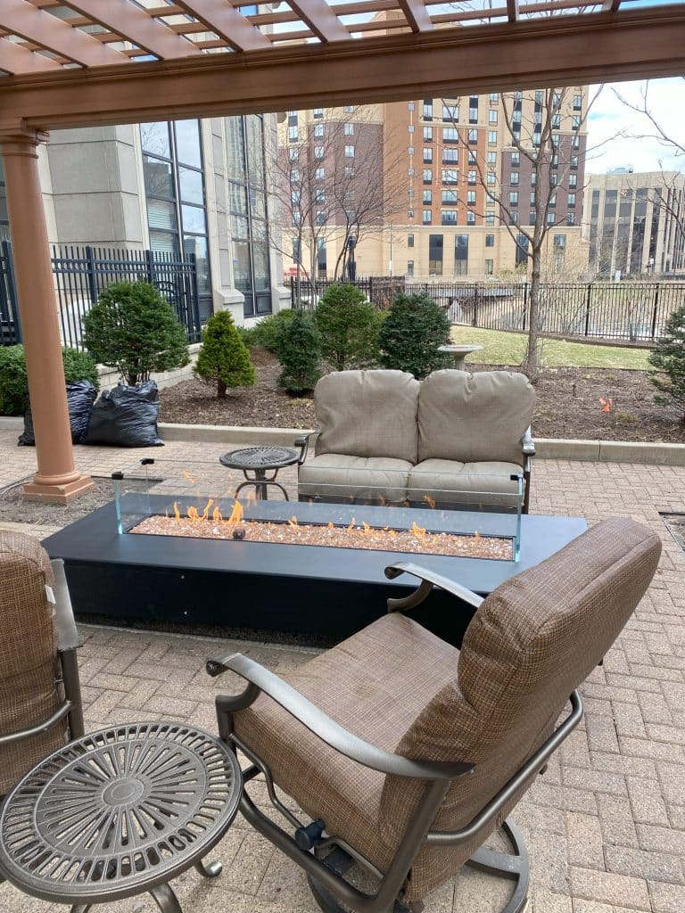 Acucraft custom outdoor gas fire table with windscreen and glass media, exemplifying superior craftsmanship, innovation, and luxury—making Acucraft the best choice for outdoor fireplaces.