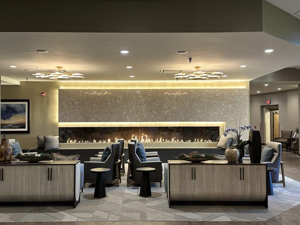 Luxurious commercial lounge featuring a custom linear gas fireplace by Acucraft with glass media and ambient backlighting