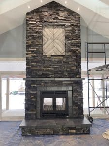 an image of a double sided wood fireplace with dark gray stone chimney