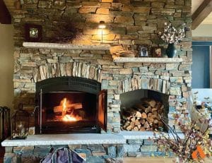 wood fireplace with stone chimney and built-in wood storage