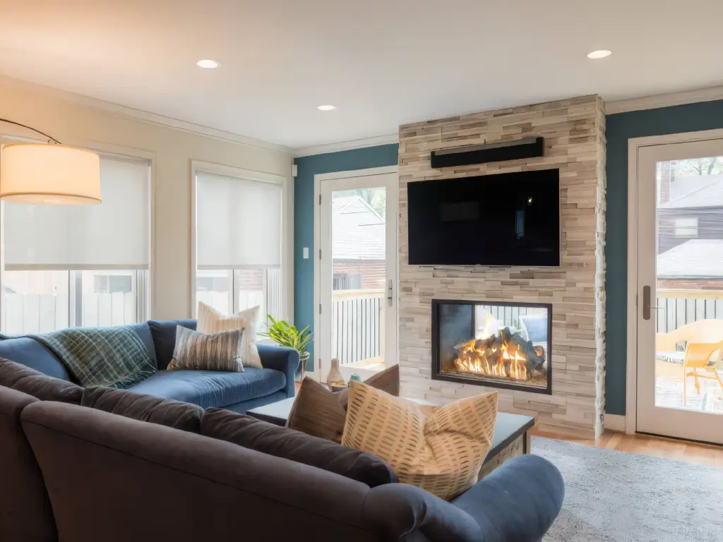 Acucraft custom gas indoor-outdoor fireplace below a television with outdoor views on both sides