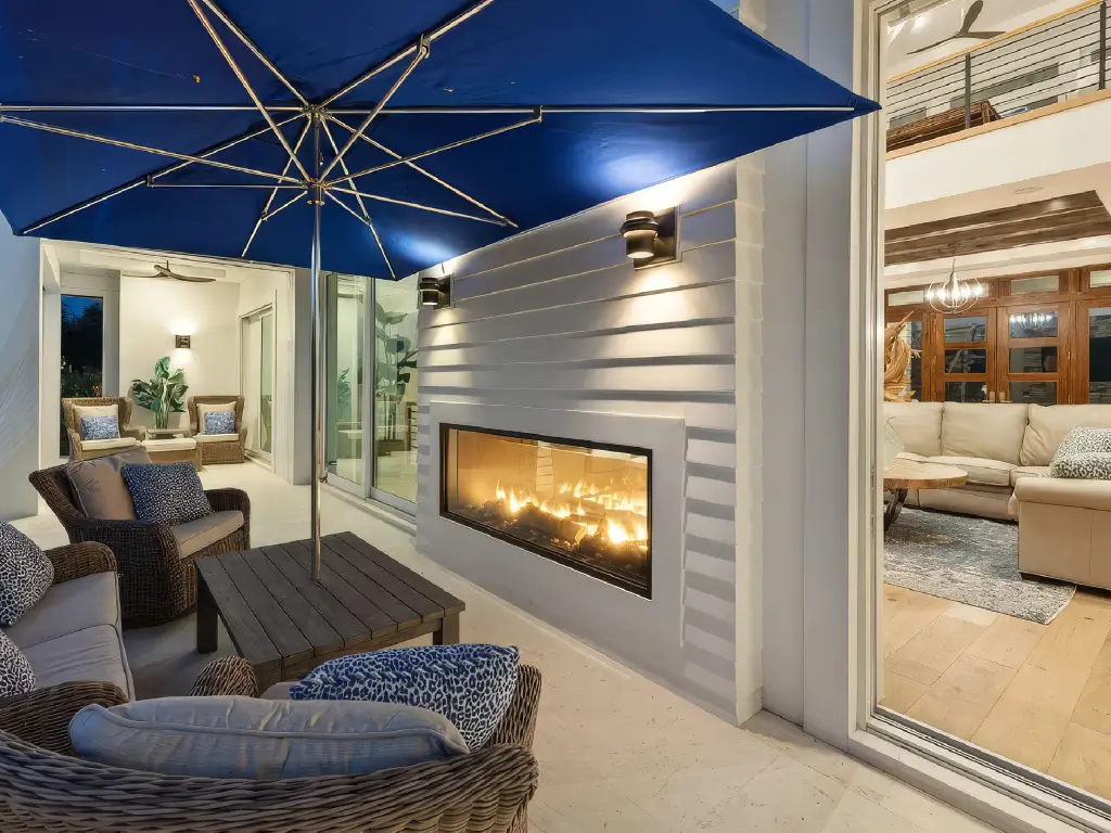 Acucraft custom see-through indoor-outdoor gas fireplace viewed from a covered patio
