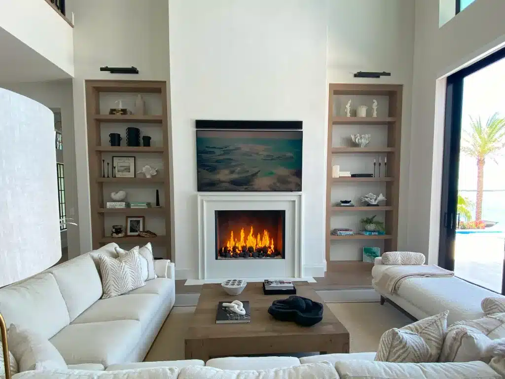 Acucraft custom single-sided open gas fireplace between built-in shelves below a television