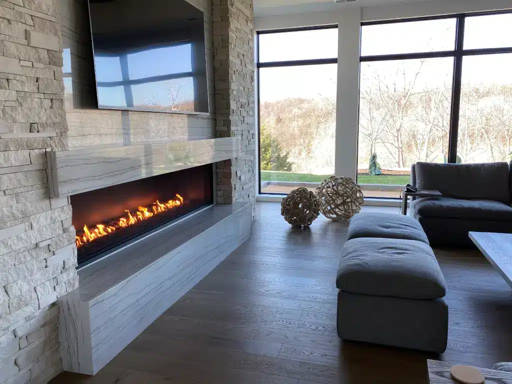 Acucraft Signature Series 8-foot open linear gas fireplace in a floor-to-ceiling stone wall