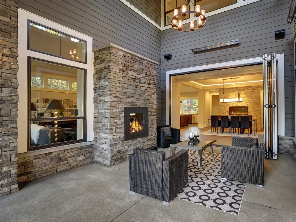 Acucraft American indoor-outdoor wood-burning fireplace beside a covered patio