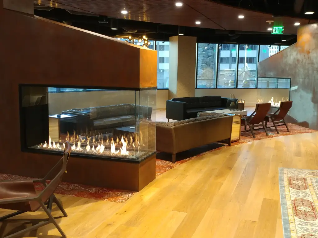 Acucraft custom gas peninsula fireplace dividing an open hospitality interior