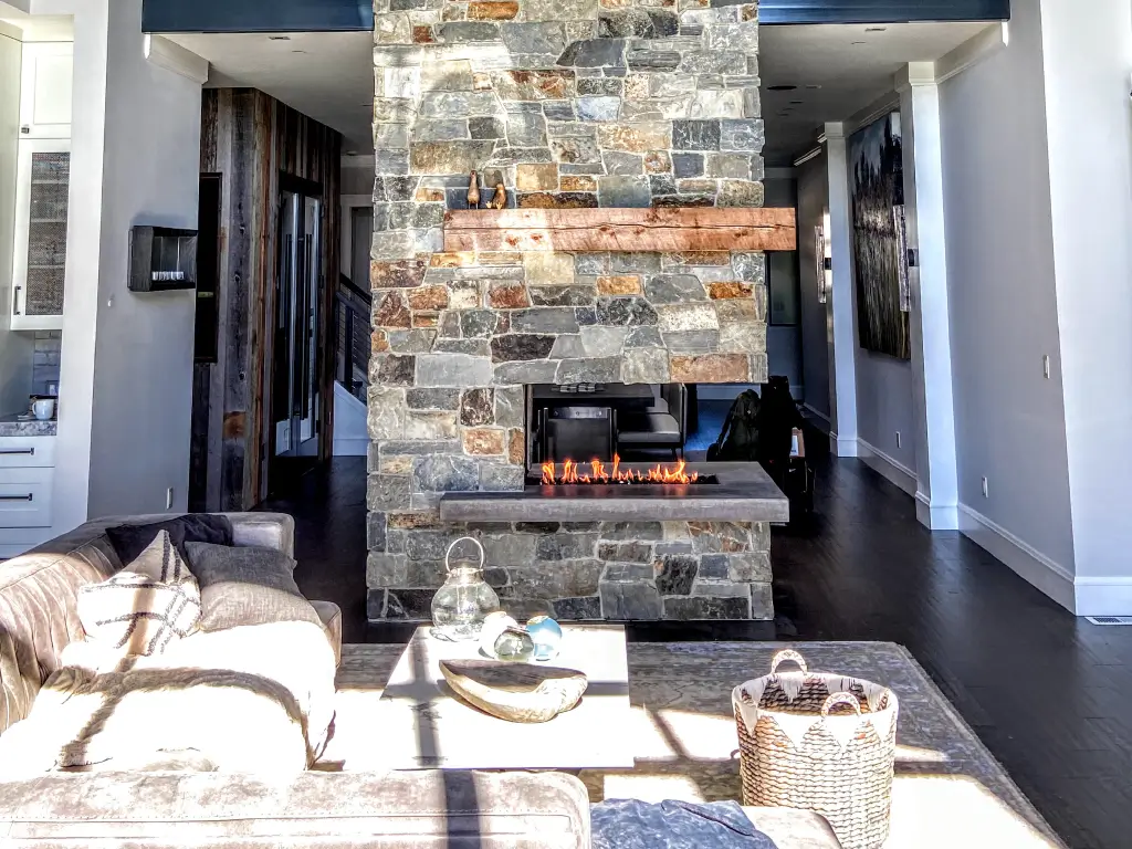 Acucraft open peninsula gas fireplace in a stone divider between living areas