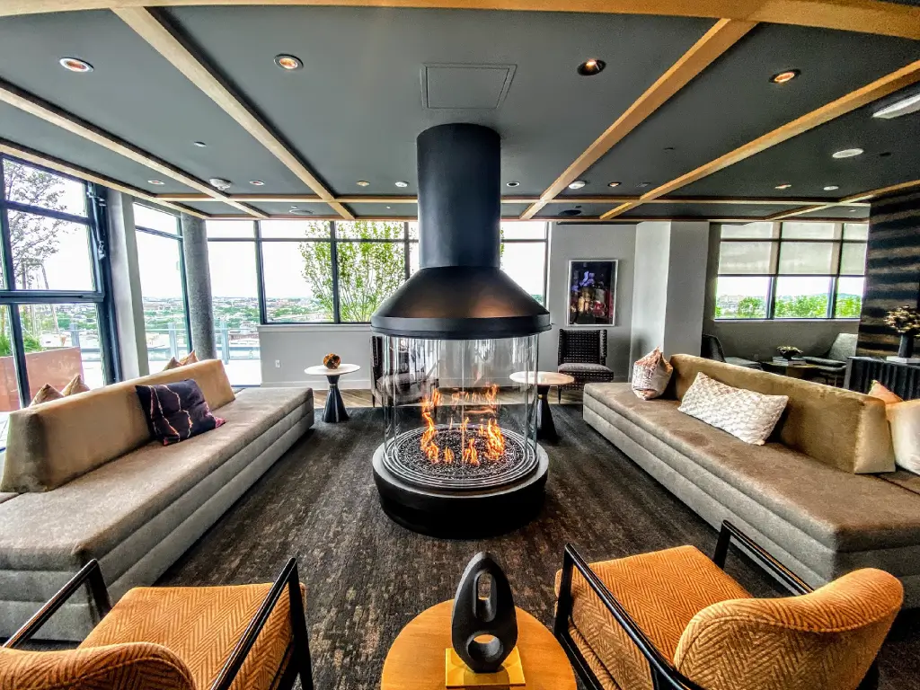 Acucraft circular gas fireplace surrounded by lounge seating and large windows.