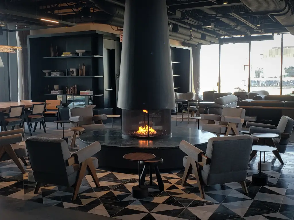 Acucraft open circular gas fireplace at the center of a lounge with seating arranged around the flame.