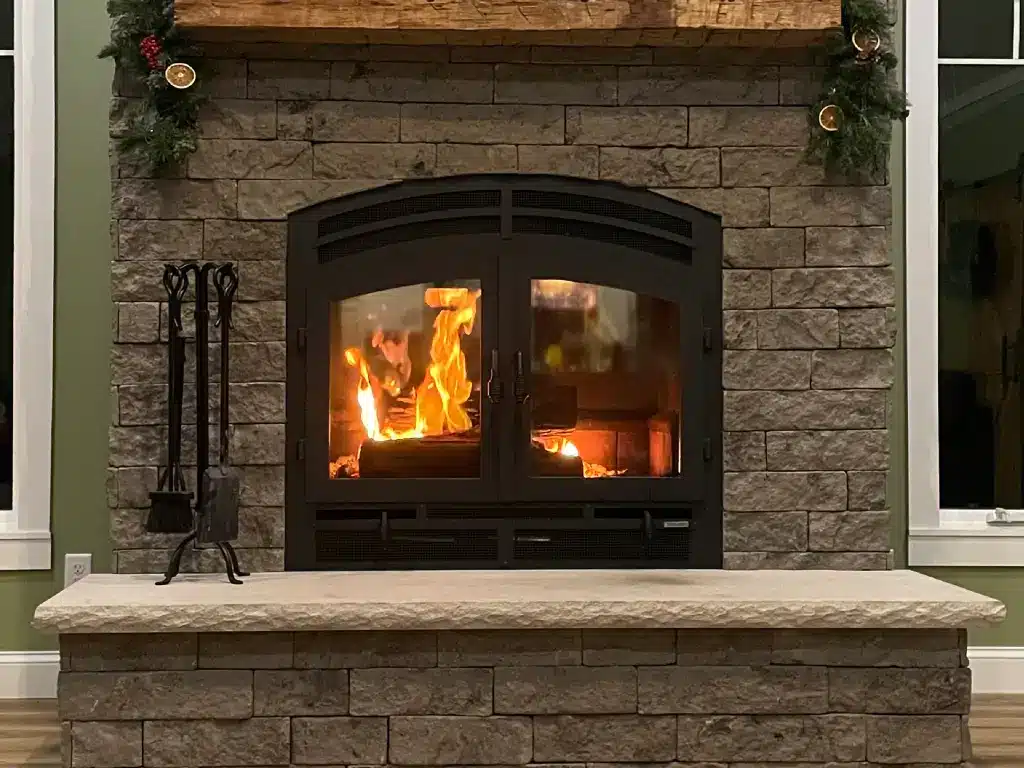 Acucraft Hearthroom 36 single-sided wood-burning fireplace with a bright fire in a stone surround.